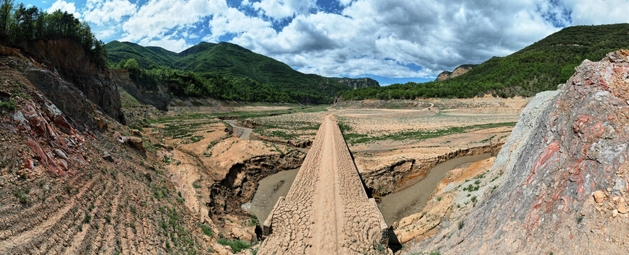 Dirt road bridge reappears from dry dam reservoir in drought