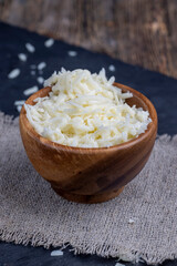 grated cheese for cooking in a wooden bowl in the kitchen
