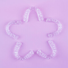 Invisible dental teeth brackets tooth aligners on pink background. Plastic braces dentistry...