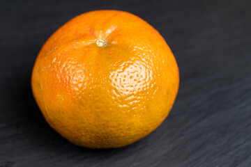 a large number of orange citrus fruits on a black slate surface - 751253161