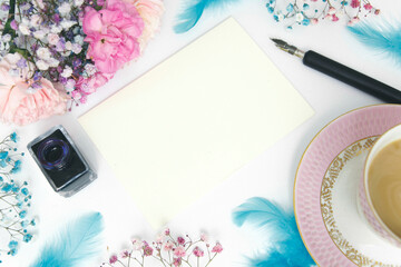 Zdjęcie aranżowane pastelowy bukiet kwiatów, filiżanka kawy i akcesoria do pisania, kaligrafii. 