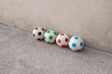 Minimal photo of colourful footballs with concrete background