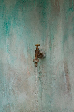 A water tap and mint green wall with texture