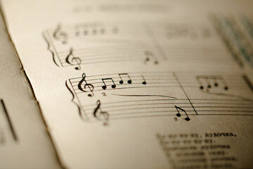 A page from a book with musical notes as a background, close-up view - obrazy, fototapety, plakaty