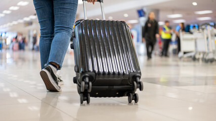 A cropped shot of a woman walking in the airport with her luggage, traveling to somewhere.