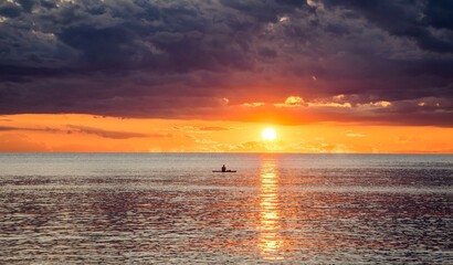 As the sun sets over the ocean, the sky transforms into a palette of warm colors, casting a tranquil glow on the water. Waves reflect the fading sunlight, creating a serene and captivating scene.