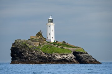 Atop the island, the lighthouse stands tall in the quiet morning. The air is calm, sea breeze...