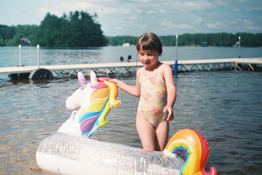 happy girl with a unicorn floaty at the lake in summer