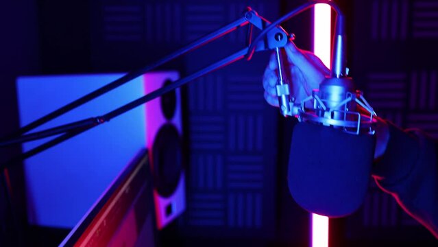 Sound engineer removes headphones from the microphone in neon LED lighting in the recording studio