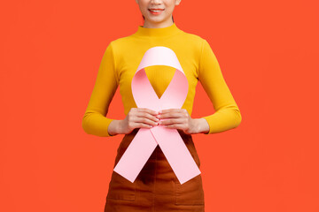 Woman in pink sweater with pink ribbon supporting breast