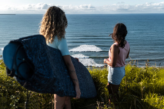 Free spirit women surfers together watching swell and waves