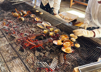 海女小屋で新鮮な伊勢海老や貝、魚を炭火焼きにする海女さん 三重県日本
