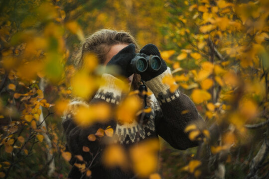 Caucasian woman birdwatching with binoculars autumn forest