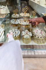 Fototapeta na wymiar Vertical photo selecting Arabic sweets at a pastry shop. Food and culture concept.
