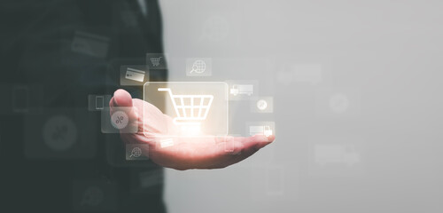Male hand holding virtual shopping cart icon, online shopping technology, e-commerce concept