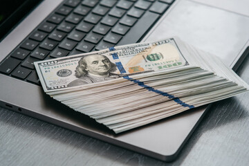 A stack of money on a laptop computer keyboard. Concept of financial savings, banking services,...