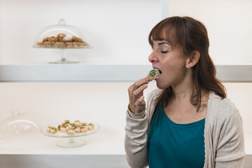 Horizontal photo woman mid adult caucasian tasting a pistachio pastry. Food and culture concept.