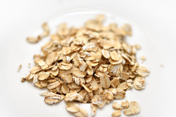 Obraz na płótnie Canvas Dry rolled oat flakes oatmeal on white plate