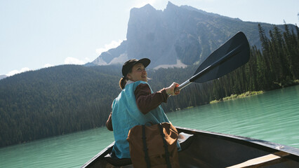 Beautiful young female canoeing through clear glacier water