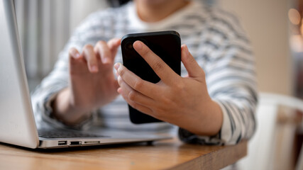 A woman using her smartphone, responding to messages, while working remotely at a cafe.