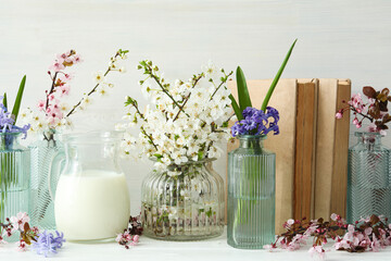 Spring twigs with flowers in a jar, with books on a light background.