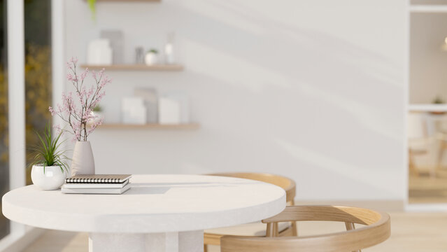 A close-up shot of a round white table with wooden armchairs in a beautiful minimalist living room.