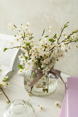 Spring twigs with flowers in a jar, with books on a light background.