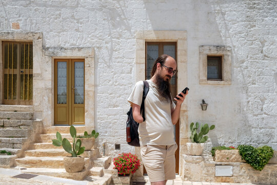 Male tourist using mobile phone In Alberobello, Italy
