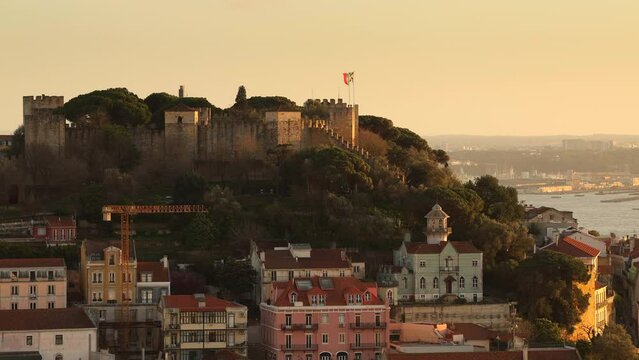Saint George Castle (S&atilde;o Jorge Castle in Portuguese) during the sunset. 4K video with this spectacular landmark building fortress on top of a hill in Lisbon with Portugal flag flying above it.