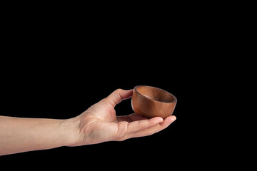 Cup wooden in hand on black background