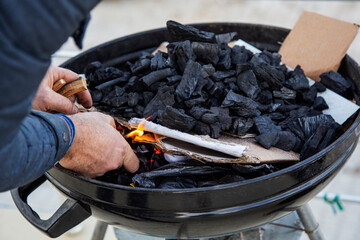 Close-up of a caucasian man burning coals in a barbecue grill