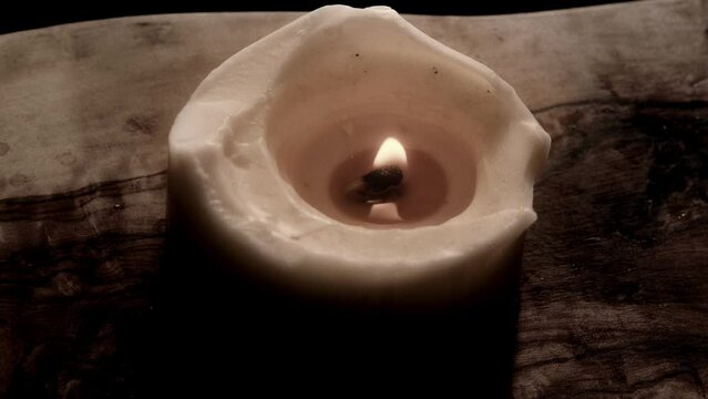 Candle placed on wood slowly moving dancing in the night.