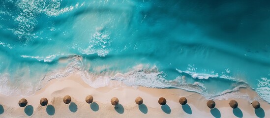 Aerial view of a serene tropical beach with crystal-clear turquoise waters, lined with umbrella shades casting shadows on the sand, perfect for travel and summer vacation concepts with copy space