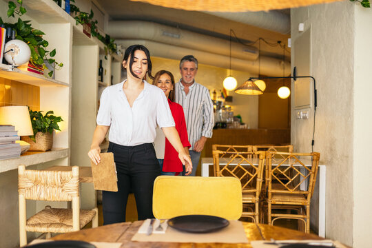 Waitress escorting customers to their table.
