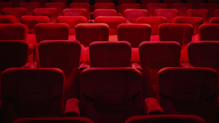 Red theater seats in dramatic lighting, waiting for an audience.