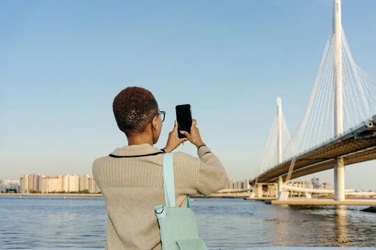 Anonymous female taking picture of bridge with smartphone
