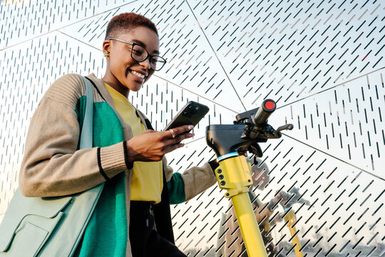 Young woman using smartphone while standing on electric scooter