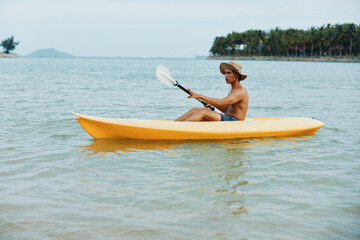 Happy Asian Man Kayaking on a Tropical Beach: Adventure and Recreation in the Sunlight