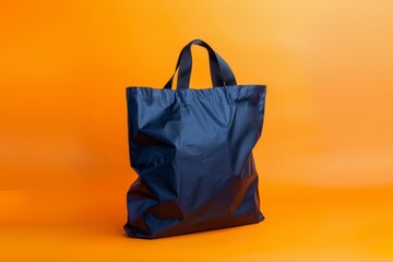 navy blue tote bag sits against a vibrant orange background, its smooth, shiny material reflecting light and creating soft highlights