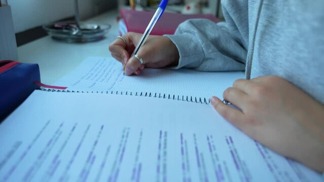 Dedicated girl studying and making notes by hand on table. Close up