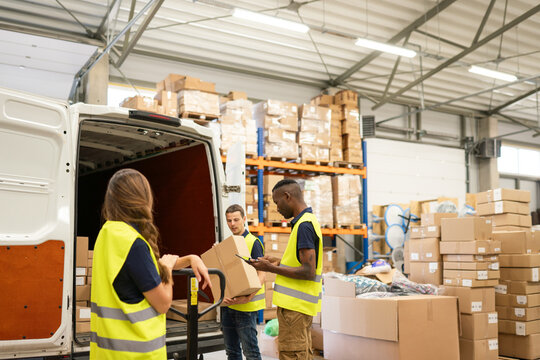 Workers Unloading Delivery Van In The Warehouse 