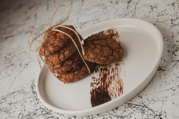 brown cookies, a few of them tied with jute string, served on a white marble floor and on a white plate
