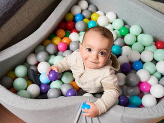 Fototapeta na wymiar a happy smiling child has fun in a ball park in his living room family time