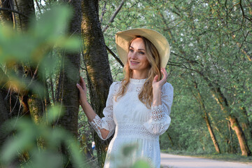 Wiosenny portret młodej ładnej kobiety w kapeluszu, w parku , wśród drzew. - obrazy, fototapety, plakaty