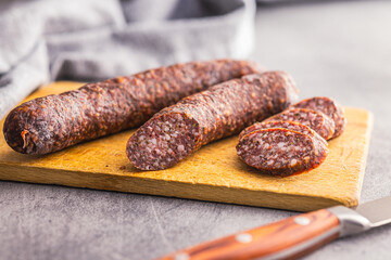 Sliced salami sausage on cutting board on kitchen table.