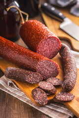 Sliced salami sausage on cutting board on kitchen table.