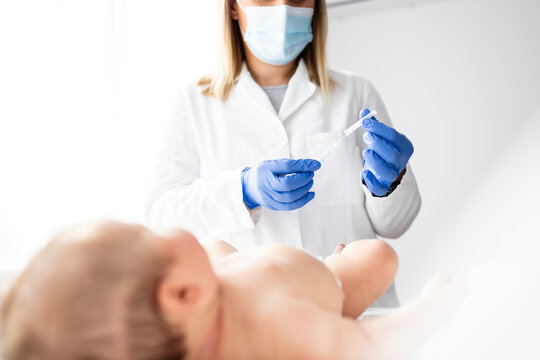 Doctor preparing needle and syringe for baby vaccination.