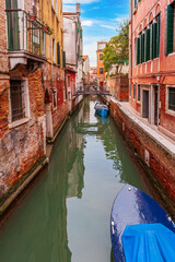 Fototapeta na wymiar Boats and gondolas at the quayside, along a canal, in Venice in Veneto, Italy