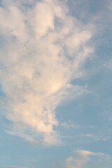 Serene sky with fluffy white clouds gently drifting, bathed in the soft, warm light of a setting or rising sun