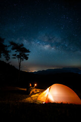 Fototapeta na wymiar nature traveling with orange camping tent on mountain with milky way background